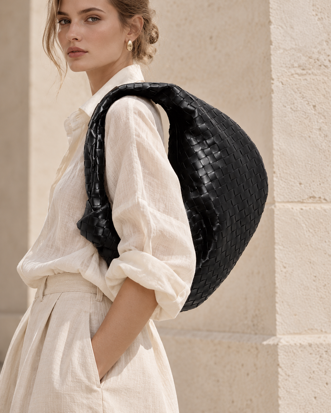 Modelo con Siena Negro de Peregrina Atelier al hombro, bolso de cuero vacuno entrelazado con asa anudada.